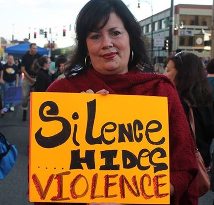 Walk a Mile walker with sign: silence hides violence